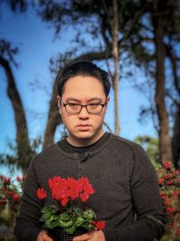 Portrait of young man standing by flowering plants