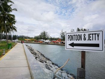 Information sign by road against sky