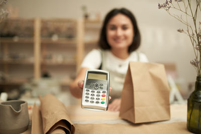 Portrait of cashier holding credit card reader