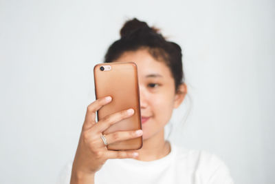 Close-up of woman using mobile phone against white background