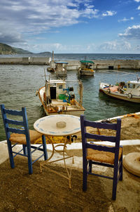 Chairs and table at beach against sky