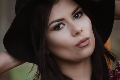 Close-up portrait of beautiful young woman wearing hat