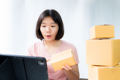 Portrait of woman holding mobile phone in box