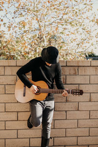 Man playing guitar against wall