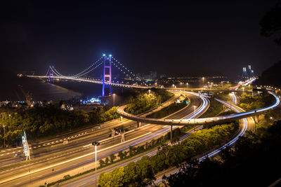 Light trails on bridge in city against sky at night