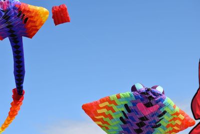 Low angle view of colorful umbrellas hanging against clear blue sky