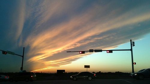 Cars on road against cloudy sky