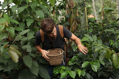 Man holding basket walking by plants