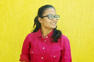 Portrait of smiling girl standing against yellow background