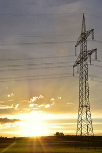 Low angle view of silhouette electricity pylon against sky during sunset