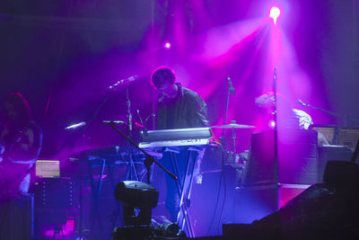 Low angle view of man playing piano on stage in music concert