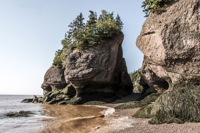 Rock formation in sea against clear sky