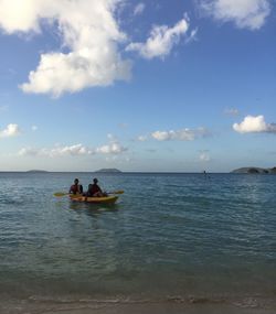 People on boat in sea against sky