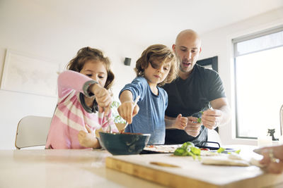 Father assisting son and daughter in preparing food at home