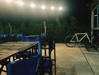 Empty chairs and table against illuminated street at night
