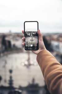 Midsection of person photographing camera on mobile phone against sky
