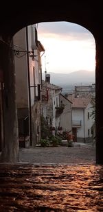 Street amidst buildings in town against sky during sunset