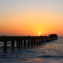 Pier on sea at sunset