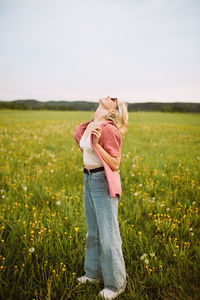 Happy young female standing in meadow in summer