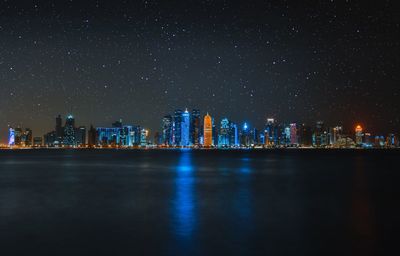 Illuminated city buildings against sky at night