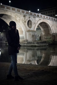 Full length of young woman standing on arch bridge