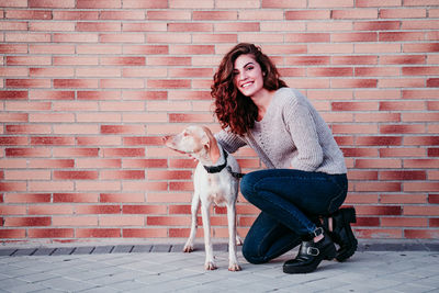 Young woman with dog on the brick wall