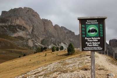 Information sign on road by mountain against sky