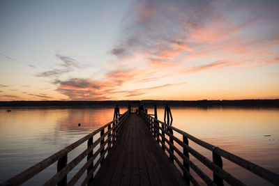 Pier over lake against sky during sunset