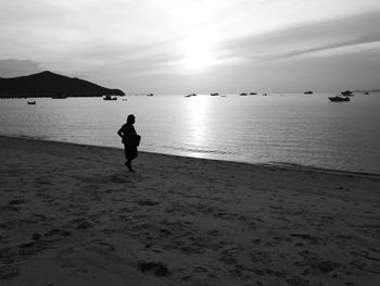 Man on beach against sky during sunset