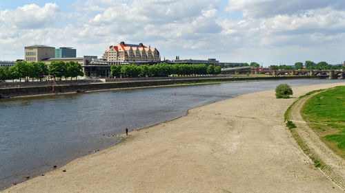 Buildings at waterfront against cloudy sky