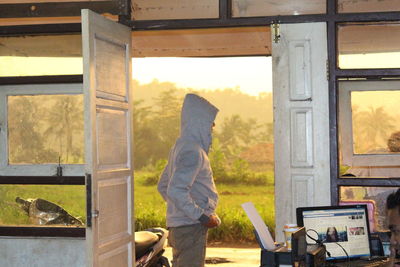 Side view of a man standing at open door