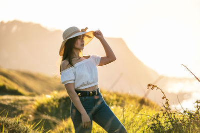 Full length of young woman standing on field against sky