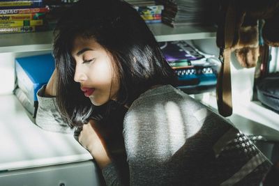 High angle view of young woman resting at table in bedroom