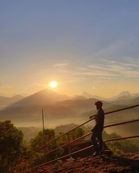 Man standing on mountain against sky during sunset