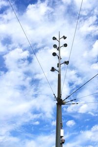 Low angle view of electricity pylon against cloudy sky