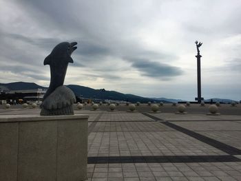 Statue of city against cloudy sky