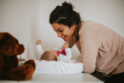 Smiling mother playing with baby girl at home