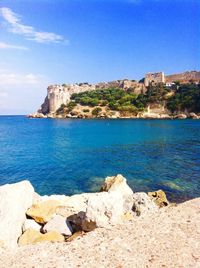 Rock formations by sea against blue sky