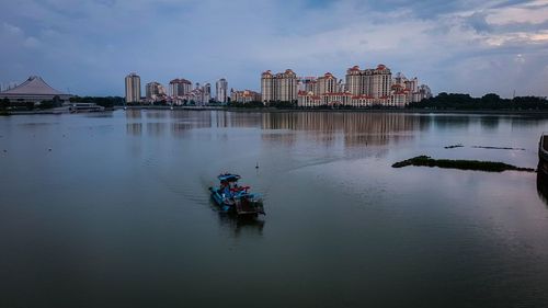 Boat in river against buildings in city