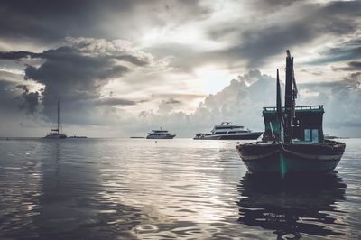 Boats in harbor against cloudy sky