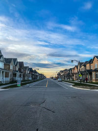 Road by buildings against sky