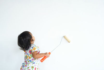 Side view of woman holding bottle against white background