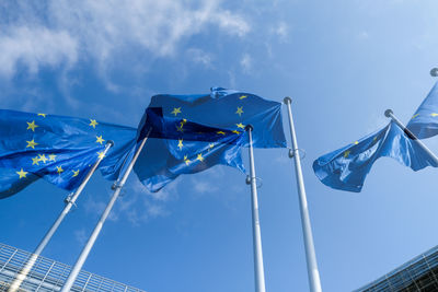 Low angle view of flags hanging against blue sky