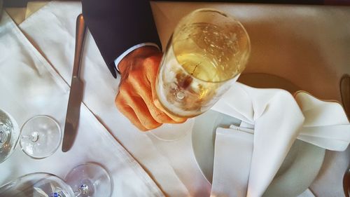 Cropped image of businessman holding champagne flute over dining table in restaurant