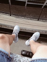 Low section of man sitting on railroad track