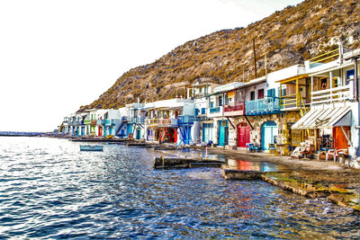 Houses by sea against clear sky