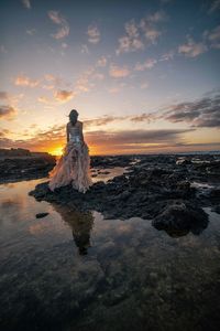 Scenic view of rocks on beach against sky during sunset