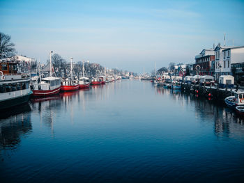 Sailboats moored in harbor against buildings in city