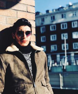 Portrait of young man standing against building