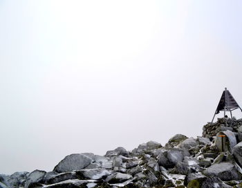 Low angle view of cross on rock against sky